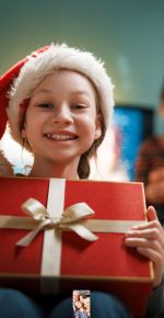 Glückliches Kind mit einem Geschenk bei der Weihnachtsfeier.