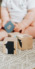 Bauklötze mit einem spielenden Baby im Hintergrund.